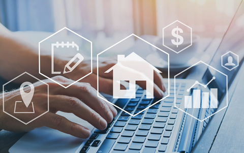 Conceptual Real Estate Image with Hands Over a Laptop and Overlayed with Icons Representing Aspects of Real Estate Business